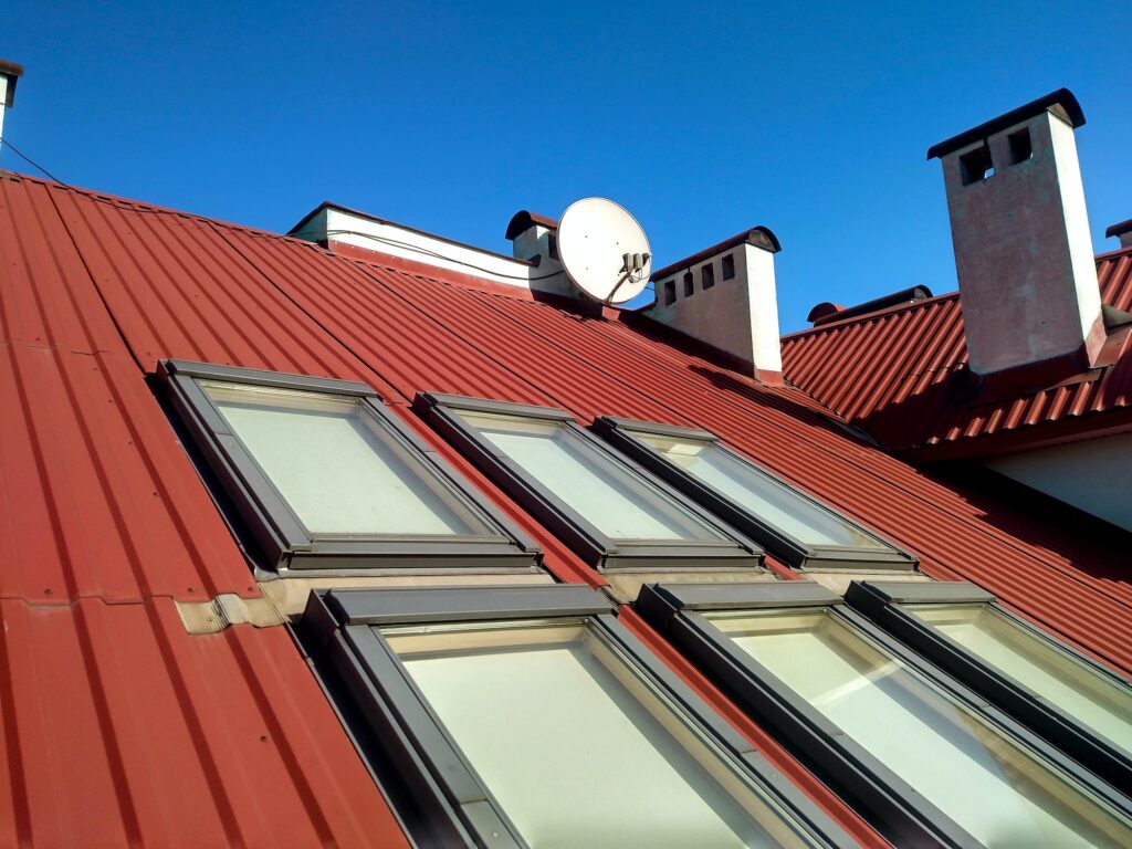 Red tiled house roof with attic windows. Roofing construction, window installation